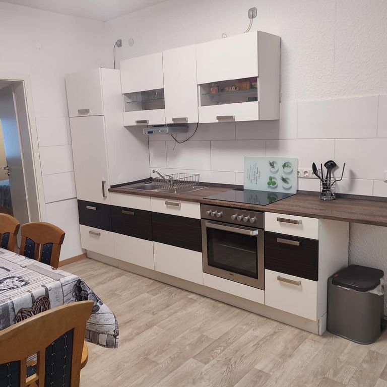 Küche mit Spüle, Herd, Backofen und Kühlschrank